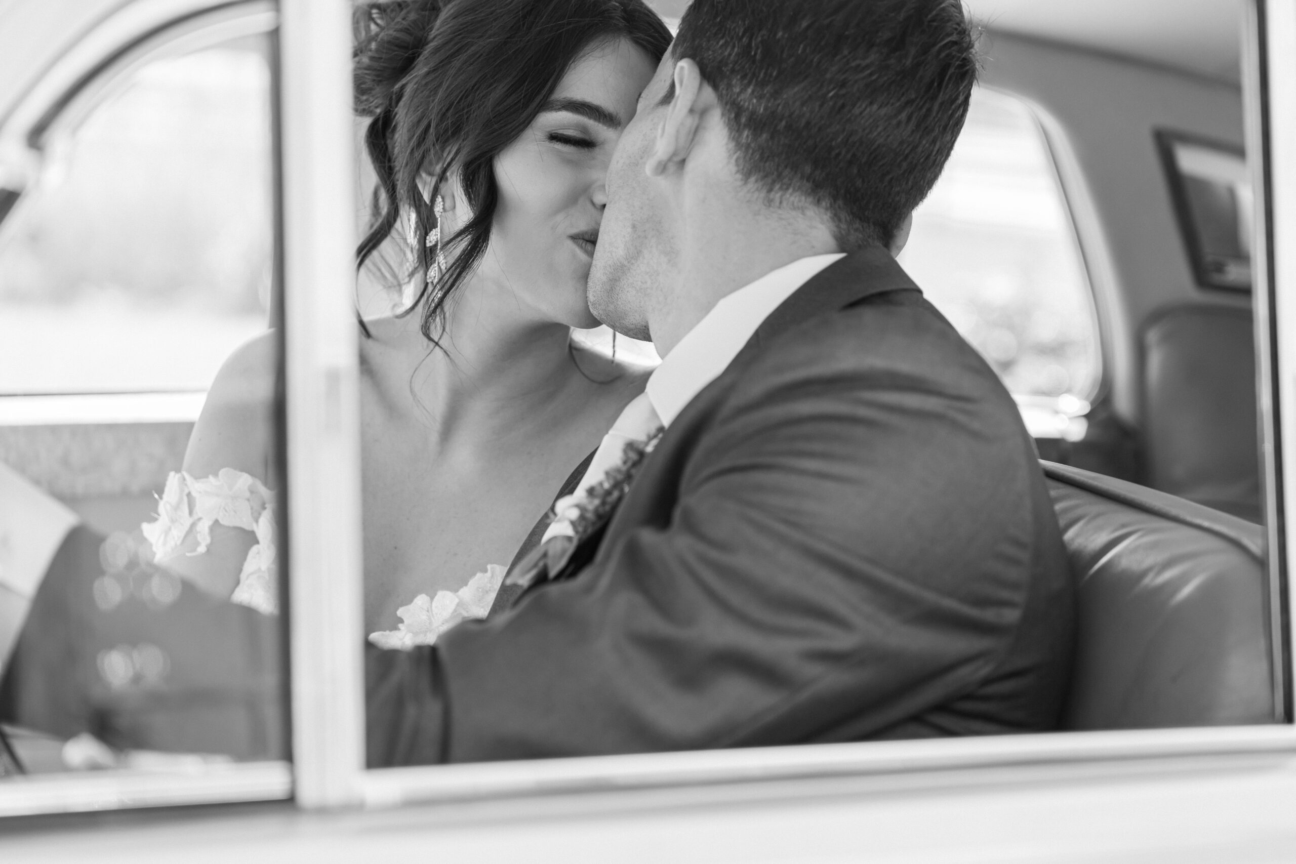 wedding couple kissing in classic car by St. Louis wedding photographers The Bennetts