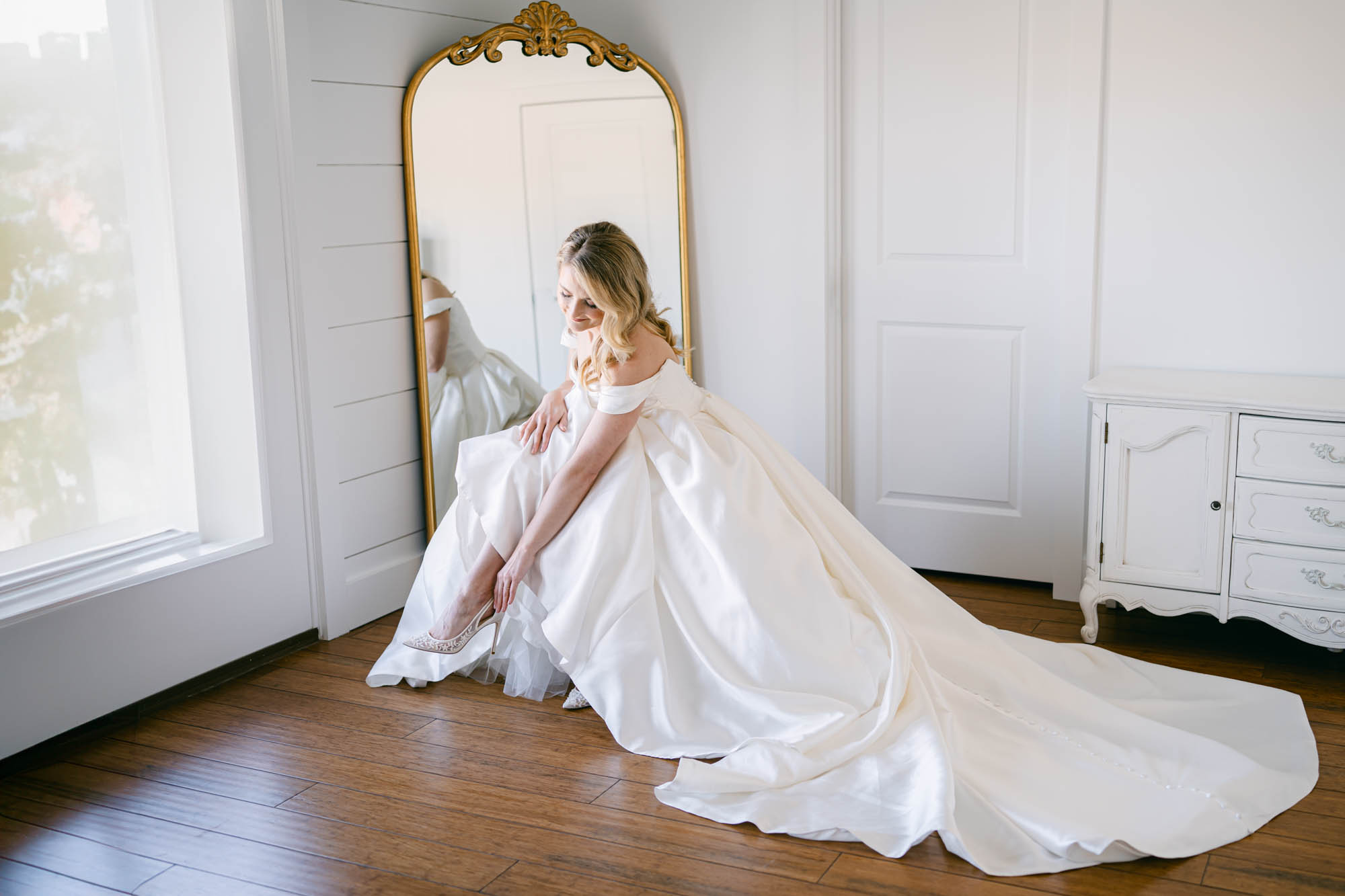 bride putting on heels in gown by St. Louis wedding photographers The Bennetts