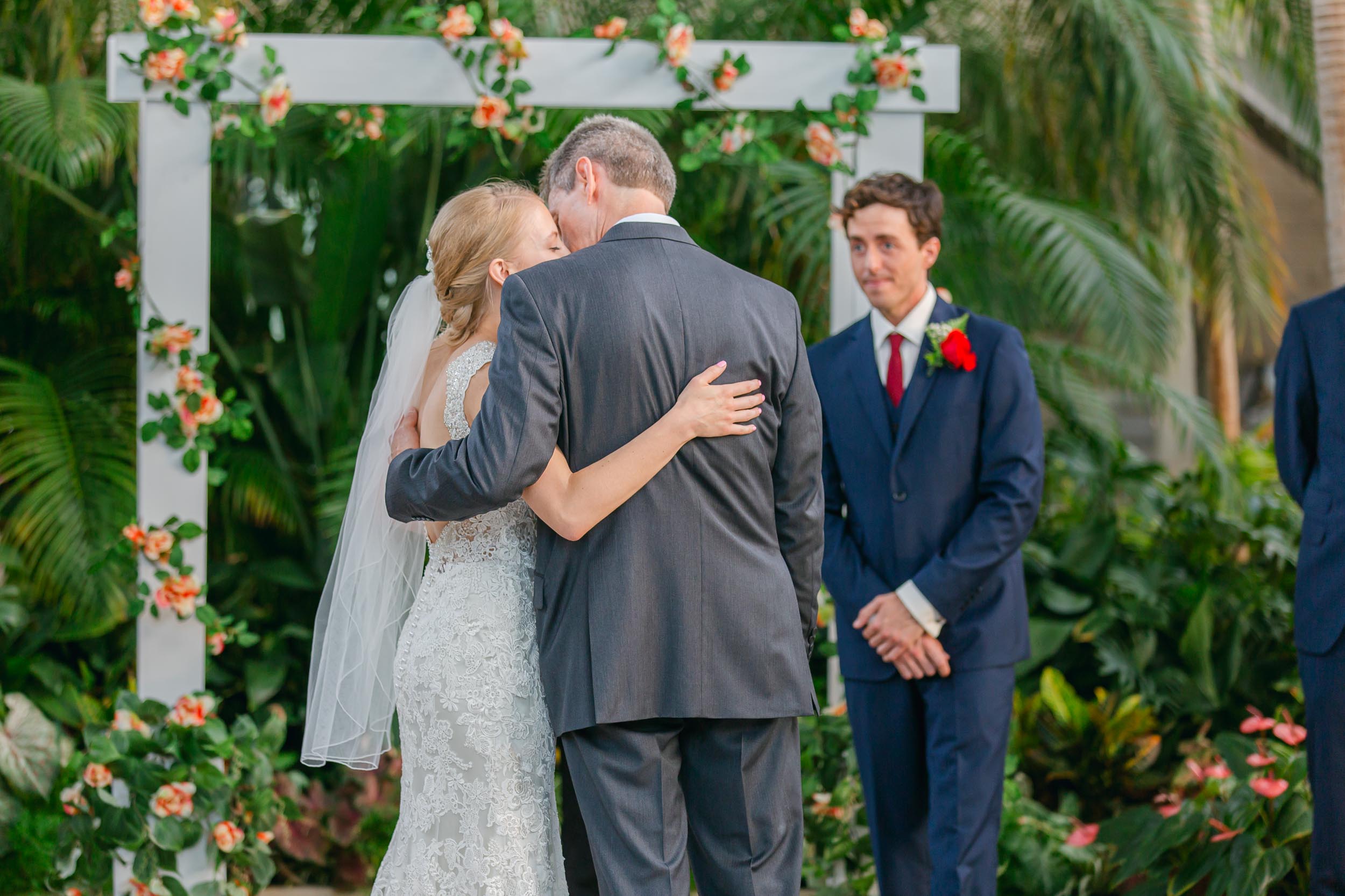 a bride and groom kissing in front of a man and woman