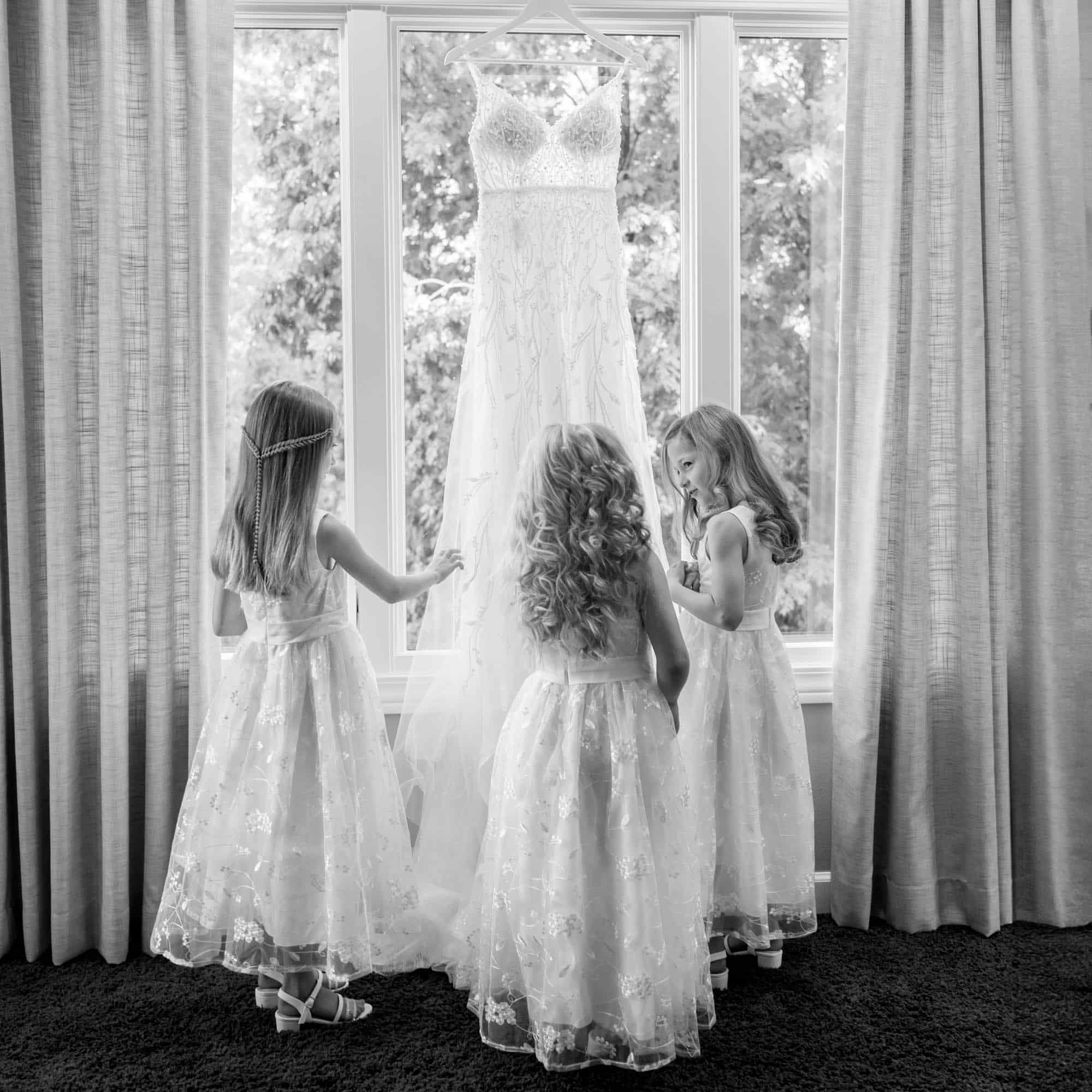 Flowergirls looking at a wedding dress by St. Louis Photographer The Bennetts