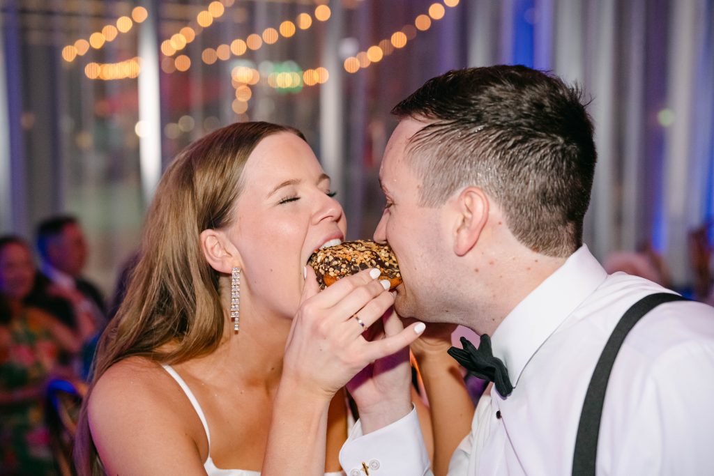 bride and groom eating donuts